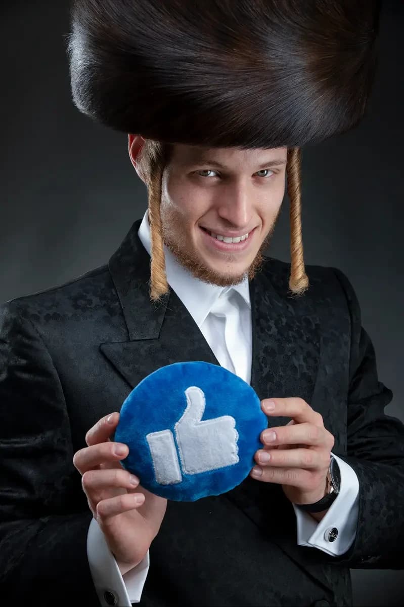 צילום תדמית עם אביזר: גבר בכובע פרווה מסורתי ובחליפה שחורה מחזיק כרית בצורת סמל ״לייק״ — צילום מושגי על רקע כהה
